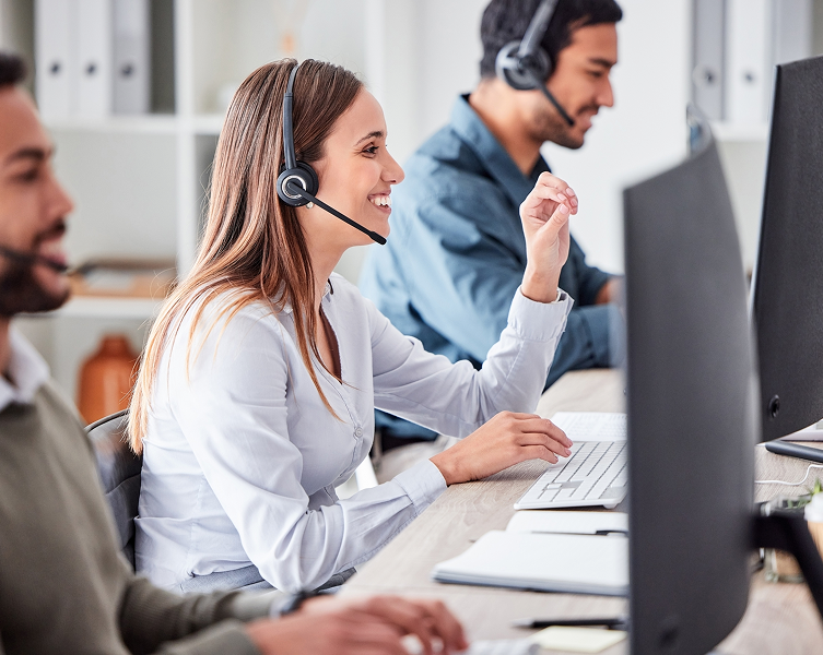 Operatrice di call center sorridente con cuffie che lavora al computer, con un collega sullo sfondo - Fondo Sanità TLC